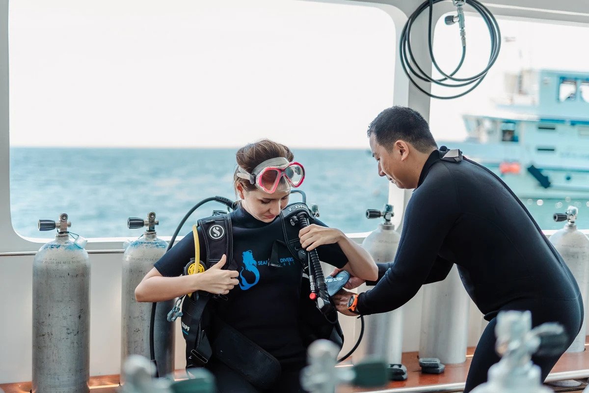 Instructor helping a beginner diver prepare scuba equipment in Phuket