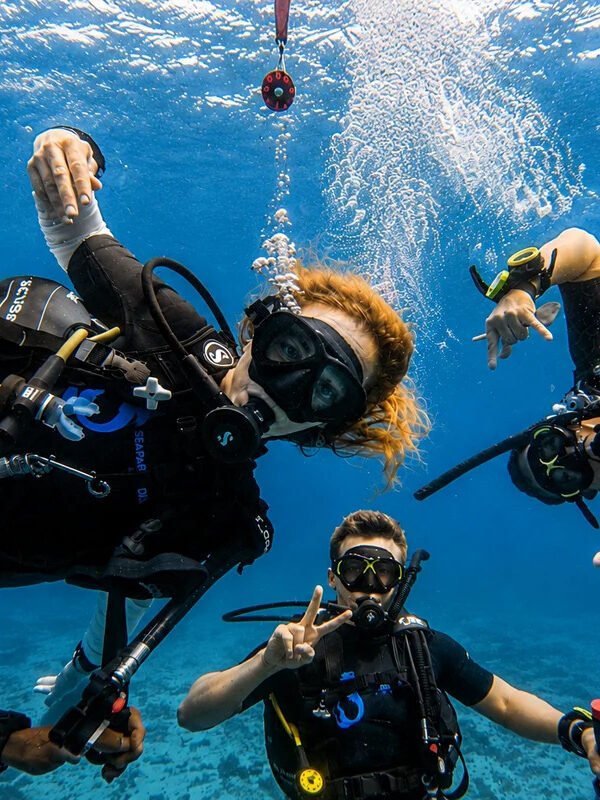 Scuba divers enjoying a fun underwater experience in Phuket with Seafarer Divers Phuket Description: A group of scuba divers enjoying a fun underwater moment in clear tropical water, ideal for promoting Phuket scuba diving experiences, beginner-friendly dive trips, and premium underwater adventures with Seafarer Divers Phuket